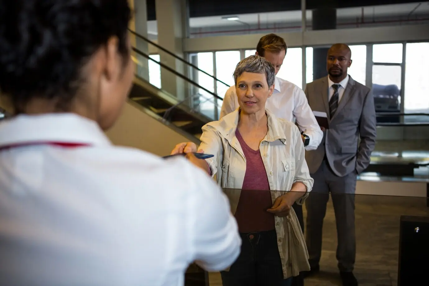 Агент стойки регистрации авиакомпании передает паспорт пассажиру.